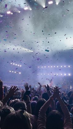 a large group of people at a concert with confetti in the air above them