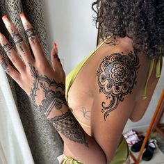 a woman with tattoos on her arm and hand is standing in front of a mirror