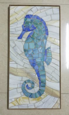 a blue and white seahorse is on display in a mosaic tile wall art piece