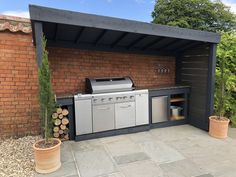 an outdoor kitchen with grill and potted plants