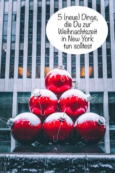 a large pile of red and white christmas ornaments in front of a tall building on a city street