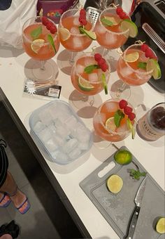 several glasses filled with different types of drinks on top of a counter next to ice cubes