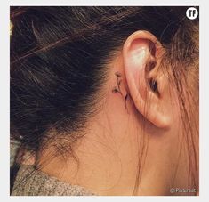 a woman's behind the ear has a small flower tattoo on her left side