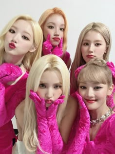 four young women in pink outfits posing for the camera with their hands on their cheeks