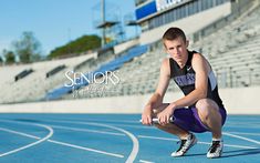 a man kneeling down on top of a blue track next to an empty bleachers