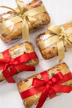 four cookies wrapped in red ribbon and tied with gold bow on white table top next to each other