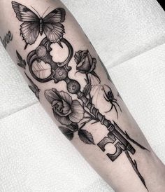 a black and white photo of a tattoo on the arm with an old key, roses and a butterfly