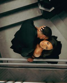 a man and woman standing next to each other on top of a stair case in an office building