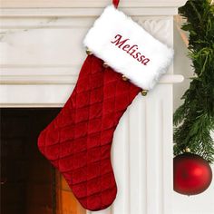 a red christmas stocking hanging from a fireplace with a name on it and a wreath