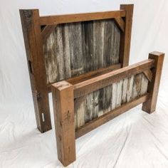 an old wooden bed frame sitting on top of a white sheet