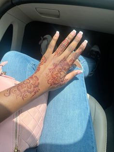 a woman's hand with tattoos on it sitting in the back seat of a car