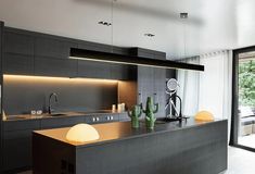 a modern kitchen with an island in front of the sliding glass door that leads to outside