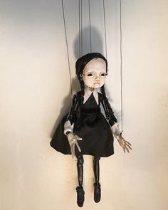 a creepy doll hanging from strings on a wall