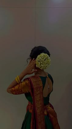 a woman in a green and gold dress holding her hands to her face while standing against a wall