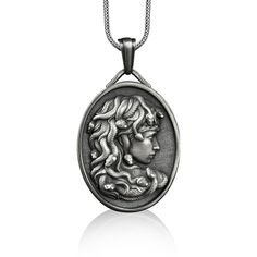 a silver pendant with a woman's face in the center, on a chain