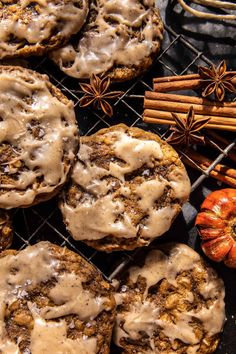 cinnamon spice cookies with icing on a cooling rack next to an orange pumpkin and star anise