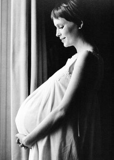 a pregnant woman standing in front of a window