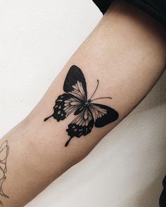 a black and white butterfly tattoo on the arm