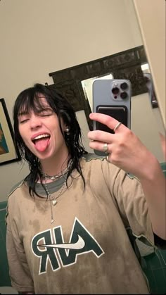 a woman taking a selfie in the mirror with her cell phone and tongue sticking out