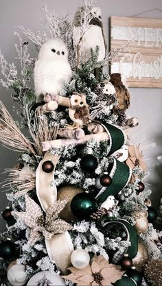 a christmas tree decorated with white and green ornaments, owl figurines and other holiday decorations