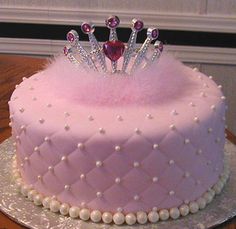 a pink cake with pearls and a tiara on top