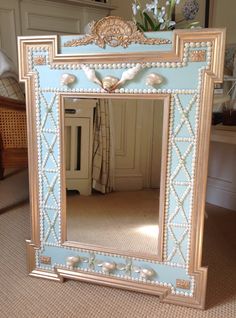 an ornate blue and gold mirror with shells on the bottom, in a living room