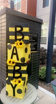 a yellow and black cake with sunflowers on the top that says b is for baby