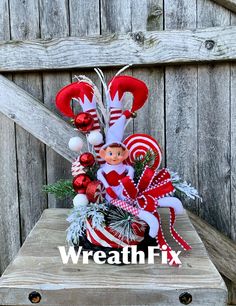 a christmas arrangement with candy canes and elf's head on top of it