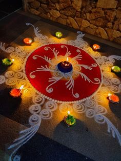 a decorated floor with lit candles and an intricately designed rangolite design on it