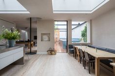 an open kitchen and dining room area with skylights on the ceiling, hardwood flooring, and white walls