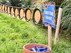 there is a sign that says shooting range in front of some barrels with markers on them