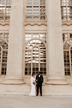 a bride and groom standing in front of an old building with large windows on each side