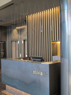 the front desk of an office building with lights hanging from it's ceiling and wood flooring