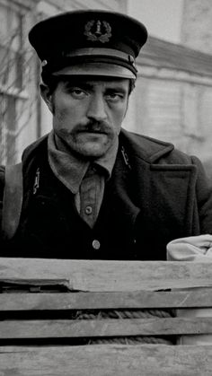 black and white photograph of a man in uniform looking over a wooden table with scissors on it