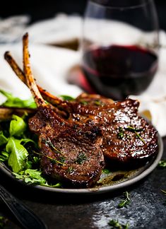 steak chops on a plate with lettuce and red wine in the background