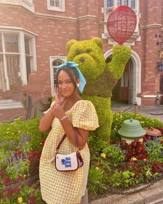 a woman standing in front of a large teddy bear with her hand up to her face