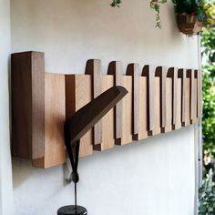 a wall mounted clock on the side of a white building with plants hanging from it's sides