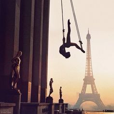 the eiffel tower in paris is silhouetted against the sky as a woman swings from a swing