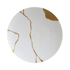 a white and gold plate with an abstract design on the rim, against a white background