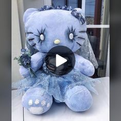 a blue hello kitty stuffed animal sitting on top of a white table next to a window