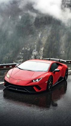 a red sports car driving down a wet road