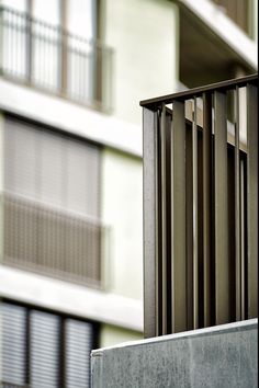 a bird is perched on the top of a metal railing in front of an apartment building