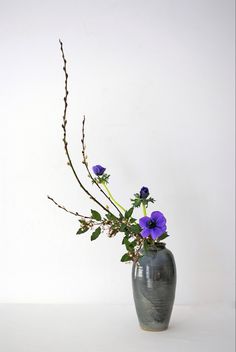 a black vase with purple flowers in it