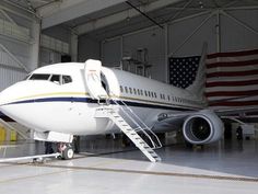 an airplane is parked in a hanger with stairs leading up to the plane's door