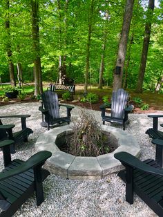 a fire pit surrounded by lawn chairs in the woods