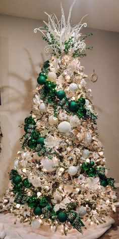 a white christmas tree with green and silver ornaments