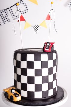 a black and white checkered cake with a toy car on top is sitting on a plate