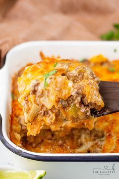 a casserole dish with meat and cheese being lifted from the casserole