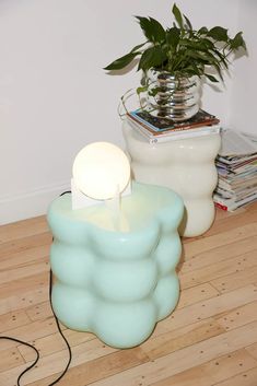 a table lamp sitting on top of a wooden floor next to a potted plant