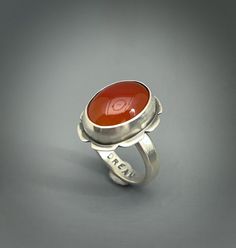 Carnelian gemstone ring set in sterling silver.  I added the word *Dream* to the inside of the ring. Women size 8 Sterling silver setting. Carnelian 12 carats 19m x13mm My signature and .925 are on the piece. All my pieces are 100% handmade by me. Please note that this ring cannot be resized because of the stone. My rings are all handmade and hand sawed. I do not cast rings. All my turquoise and other gemstones are sourced from highly reputable dealers. All my pieces are genuine. Some stones may have inclusions. That is the nature of the gemstone.  I try my outmost best to take pictures that reflect the true color of the stones. Some monitors may vary and affect the way you might see it but hopefully not. The fit is different on the wider bands. I try and accommodate for that size differen Anniversary Carnelian Rings With Polished Finish, Unique Carnelian Ring For Anniversary, Polished Carnelian Ring, Gemstone Rings Unique, Cast Rings, Red Gemstone Ring, Hand Saw, Red Gemstones, Ring Women